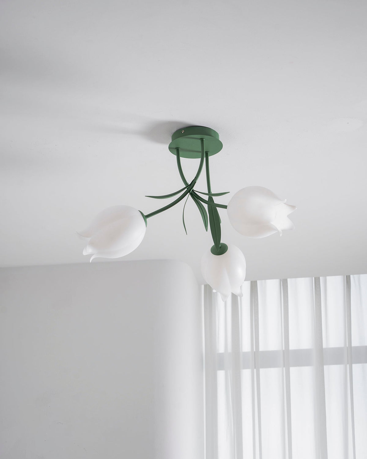 Near a bright, sheer-curtained window, this Clérachic ceiling light in green hangs in a minimally furnished room.