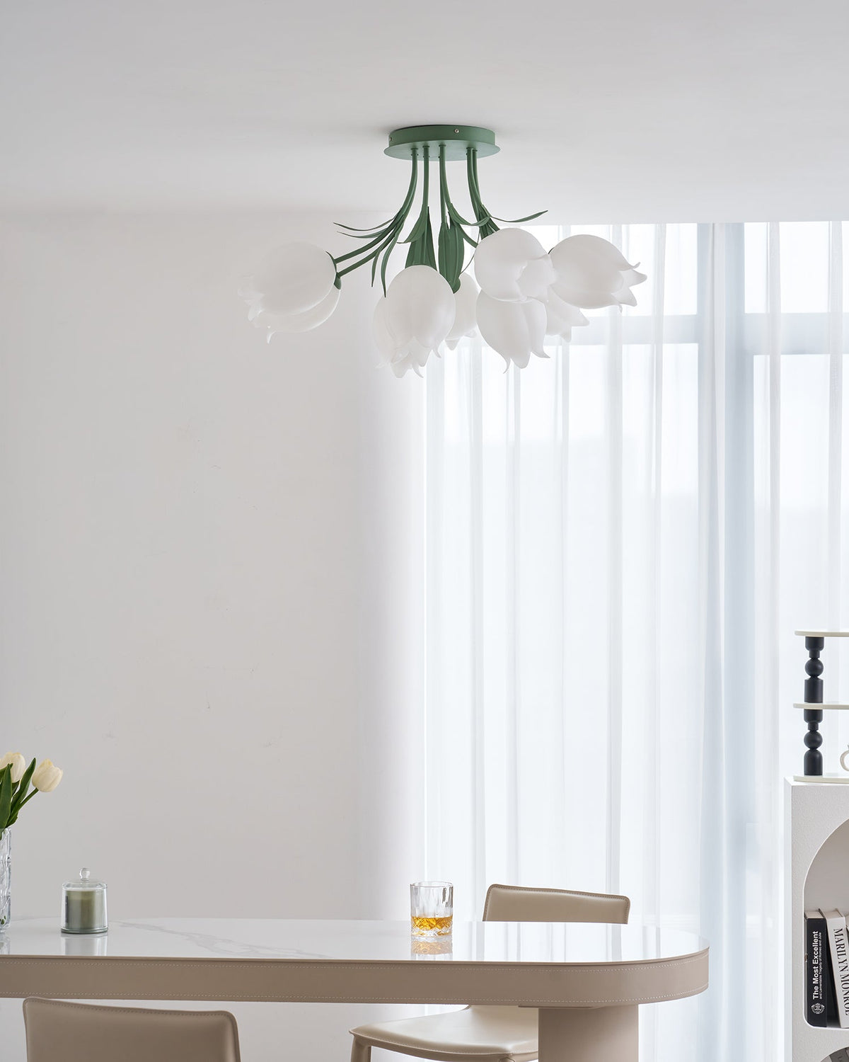 Above a dining table set with books, a mug and a glass, this Clérachic ceiling light in green hangs unlit.