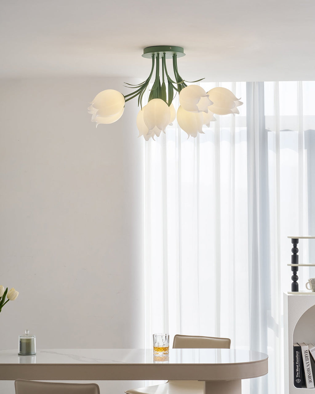 Above a wider dining scene with books, a glass and a mug, this Clérachic ceiling light in green hangs unlit.