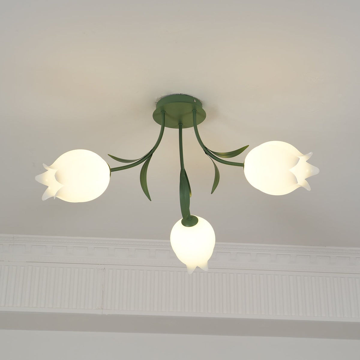 Hanging near a cove moulding, this Clérachic ceiling light in green shows its stem and leaves above the shades.
