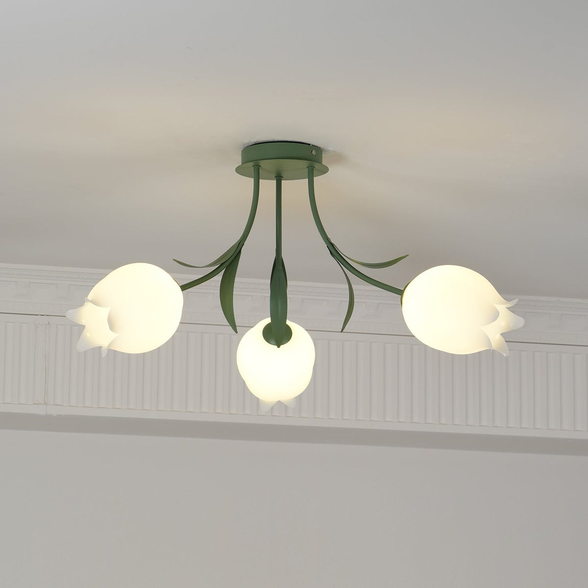Glowing warm beneath a cove moulding, this Clérachic ceiling light in green has all three shades lit at once.
