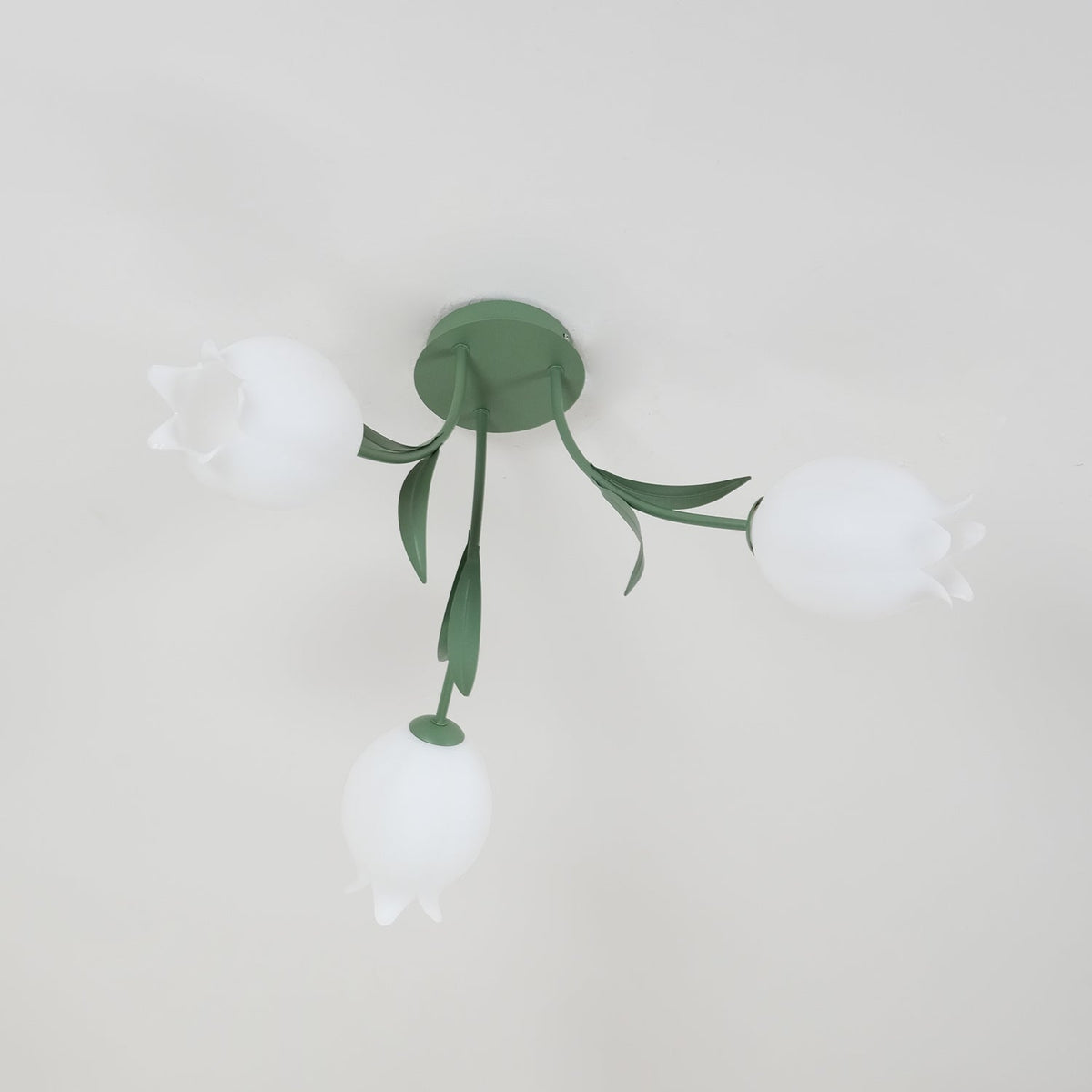 Near a cove moulding, this Clérachic ceiling light in green hangs unlit, seen from a slightly different side angle.