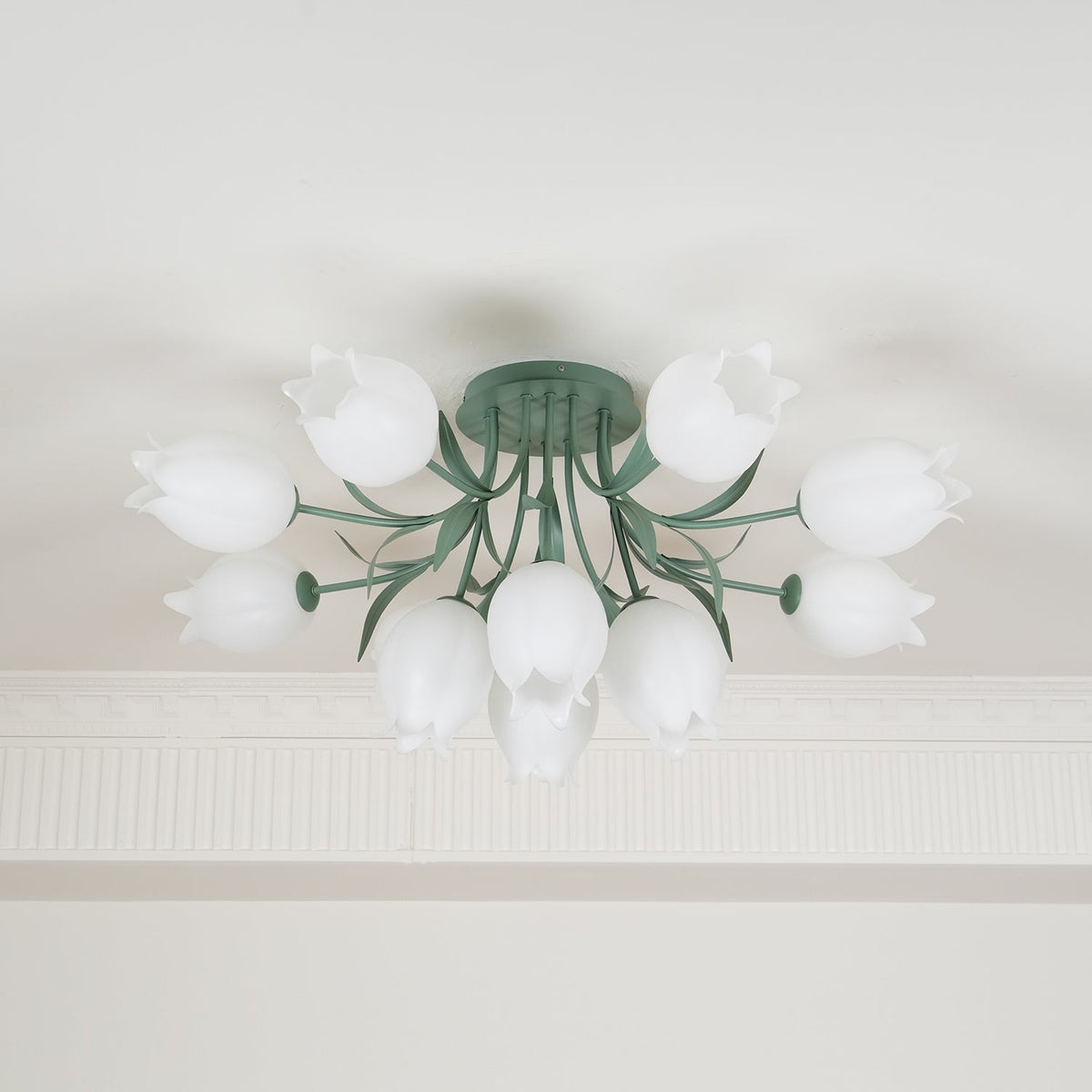 Near a cove moulding, this Clérachic ceiling light in green shows its cluster of shades softly lit from within.