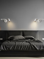 Swing arm wall lamp lit warmly above a bedside table