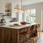 A wood-fronted kitchen island holds a fruit bowl beneath this brass Clérachic chandelier.