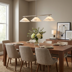 This Clérachic chandelier in brushed nickel lights a dining table set with white flowers.