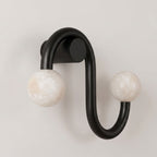 Set against a plain background, the matte black finish of this Clérachic sconce forms a sinuous S-curve.