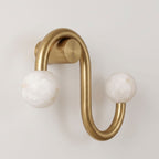 Cropped close on a plain background, this Clérachic sconce's brass finish shows the texture of its two alabaster globes.