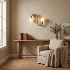 Beside a wooden bench and upholstered armchair, this Clérachic sconce's nickel finish lights a plaster living room wall.