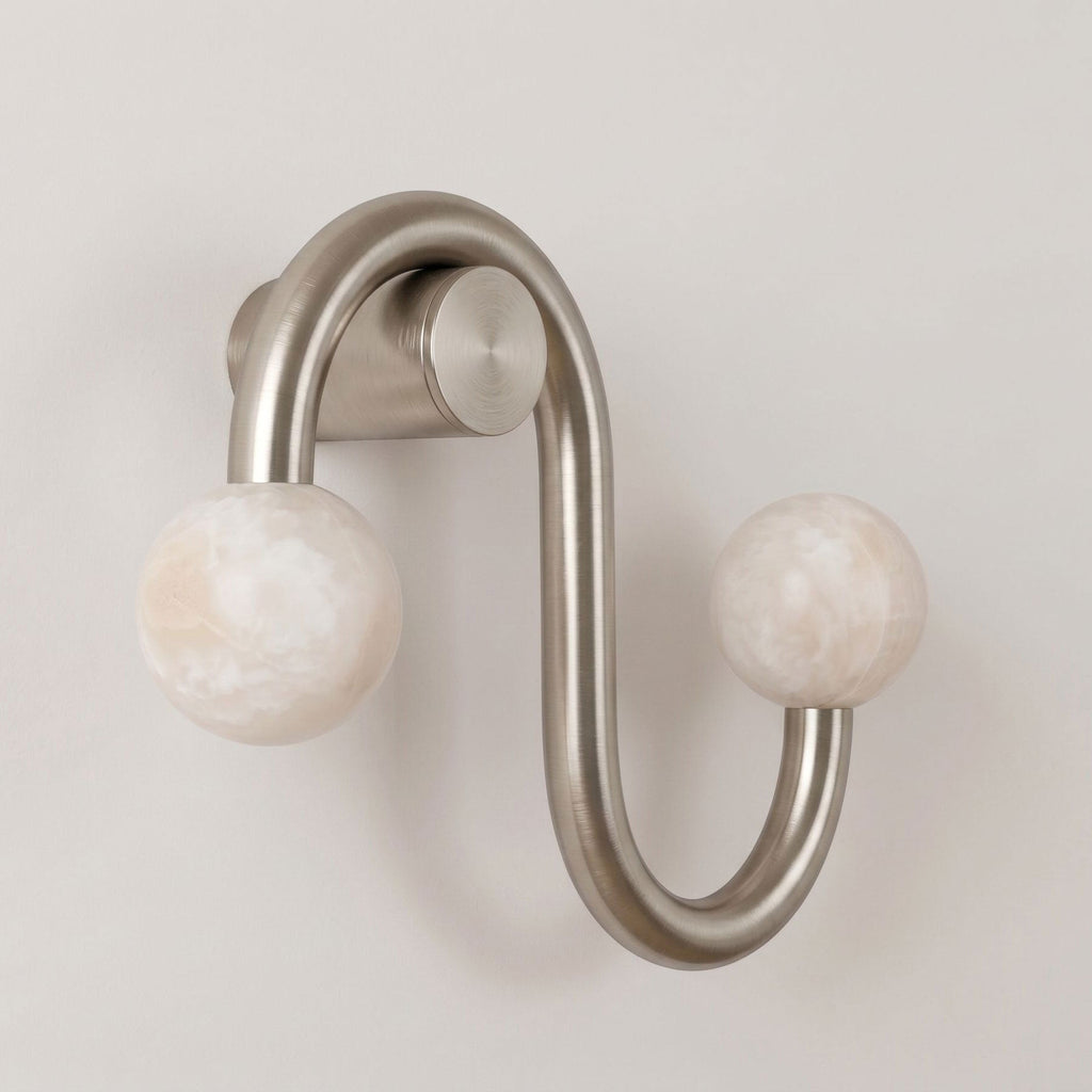 Shown unlit on a plain backdrop, the nickel finish of this Clérachic sconce curves twice before each alabaster globe.