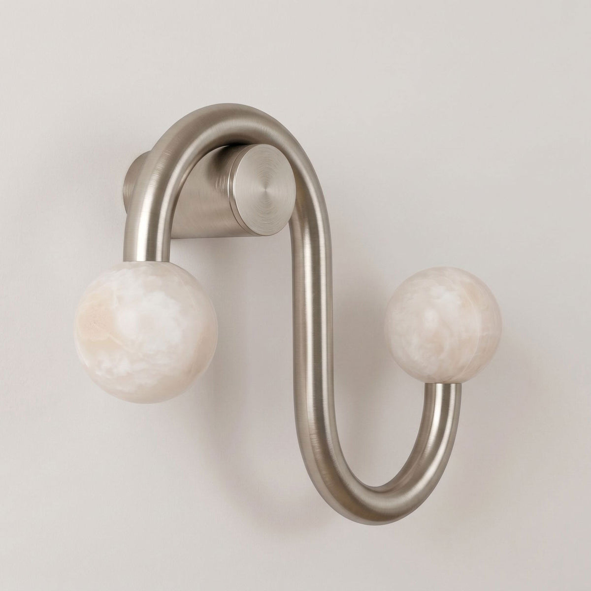Shown unlit on a plain backdrop, the nickel finish of this Clérachic sconce curves twice before each alabaster globe.