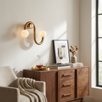 Beside a decanter and stacked books on a walnut sideboard, this Clérachic sconce's brass finish lights the corner.