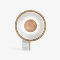 Clérachic gold-ringed disc table lamp on a plain white background, its rectangular white marble foot standing below the softly lit ring.