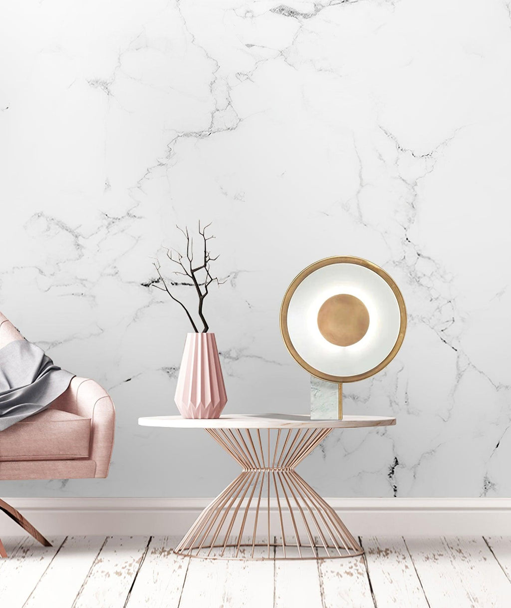 Clérachic disc lamp on a marble accent table beside a dusty pink velvet armchair, a wire-frame round table and marbled wall behind.