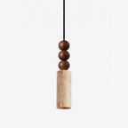 Close view of this Clérachic pendant's stacked wood beads above a travertine cylinder, shown against a plain grey backdrop.