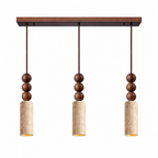 Three Clérachic pendants hang from a single wood canopy, each travertine cylinder topped with stacked wood beads, shown on white.