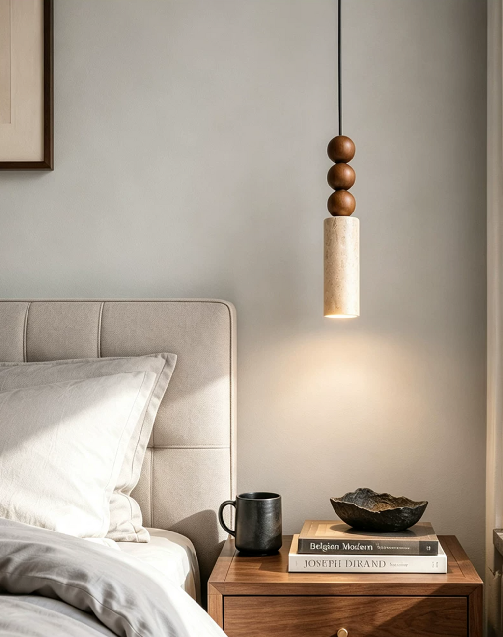 Above a wide upholstered headboard, this Clérachic pendant lights a nightstand of books and a mug.