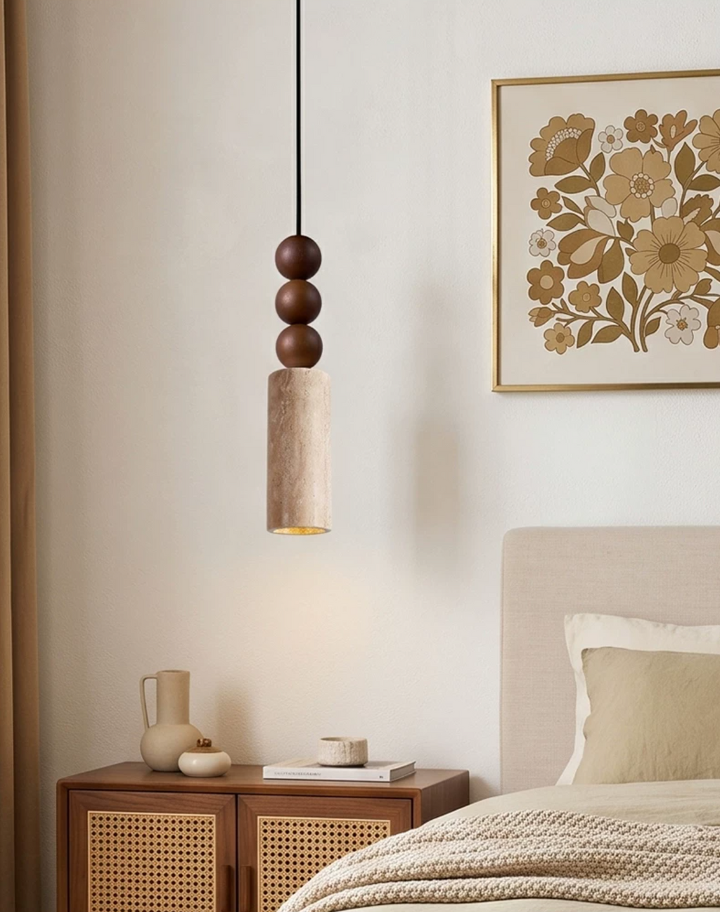 A ceramic jug tops the rattan-fronted console beneath this Clérachic pendant, lit beside a gold floral print.
