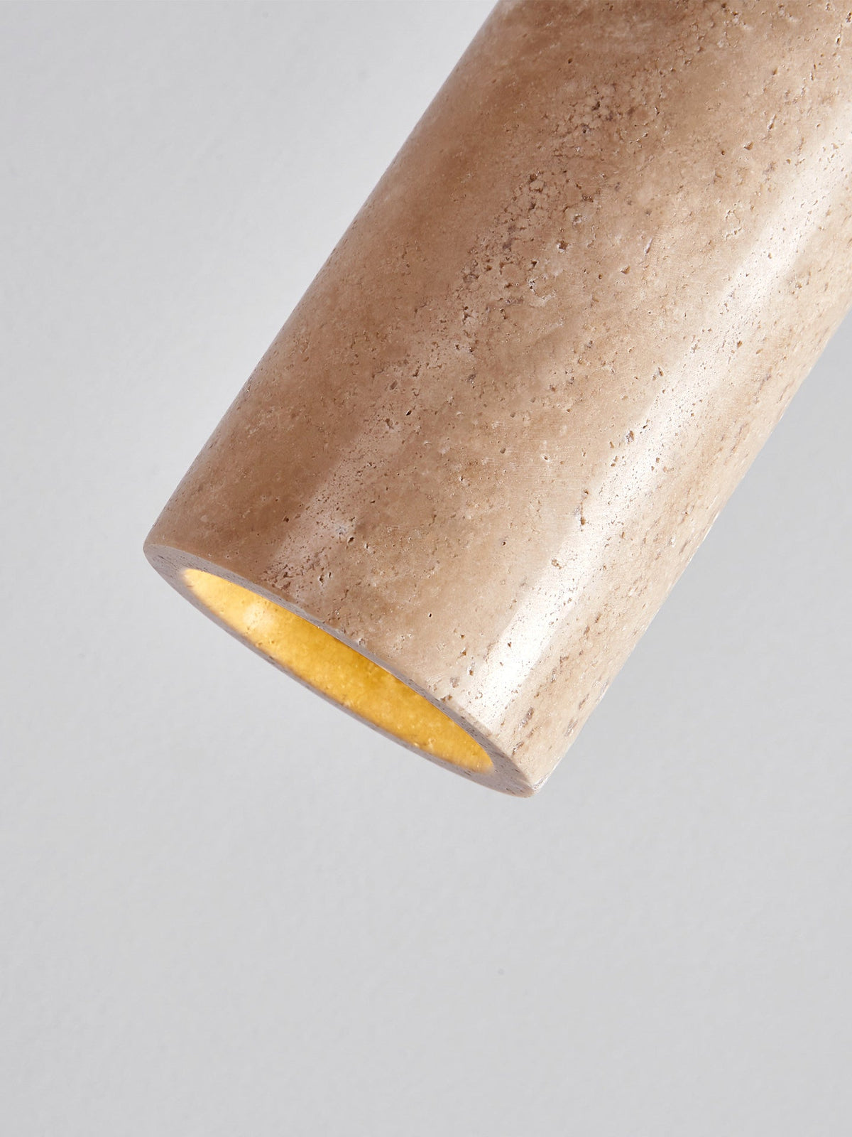 Close angled detail of the travertine cylinder on this Clérachic pendant, showing its textured surface and gold-lined interior.