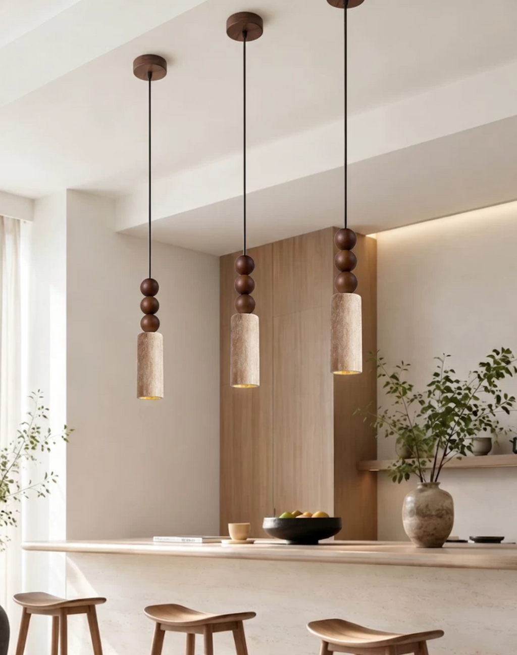 Three Clérachic pendants hang in a row above a kitchen island with wood stools and a bowl of citrus.