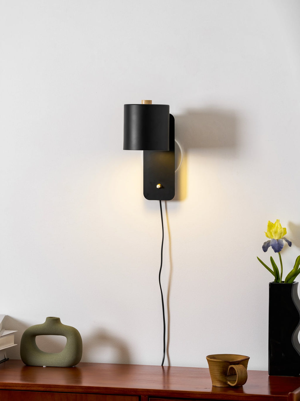 Cylinder wall lamp glowing softly on a neutral painted wall