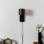 Cylinder wall lamp with warm glow mounted in a cozy bedroom