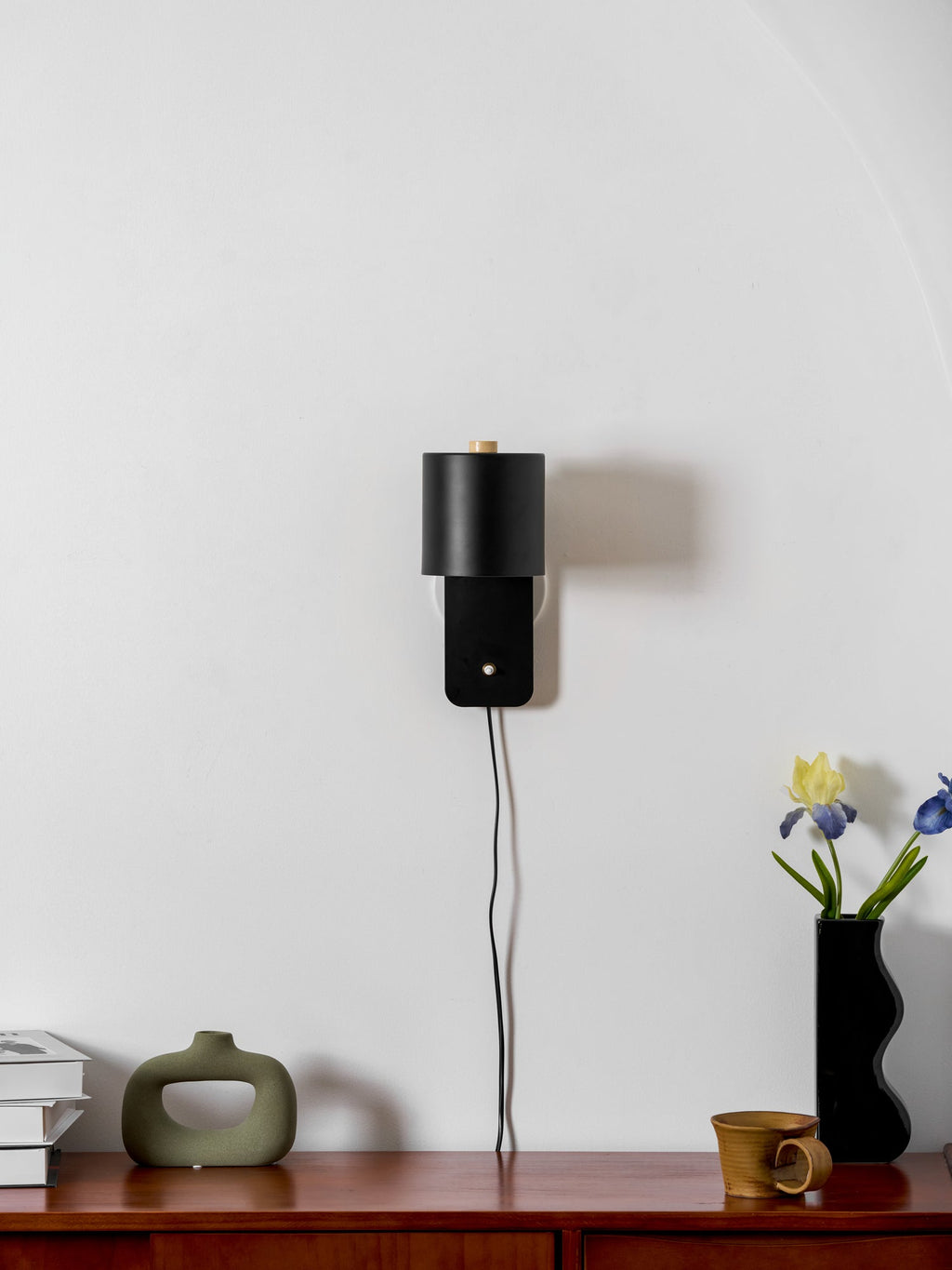 Minimalist cylinder wall lamp shown tilted upward on a wall