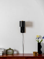 Minimalist cylinder wall lamp shown tilted upward on a wall