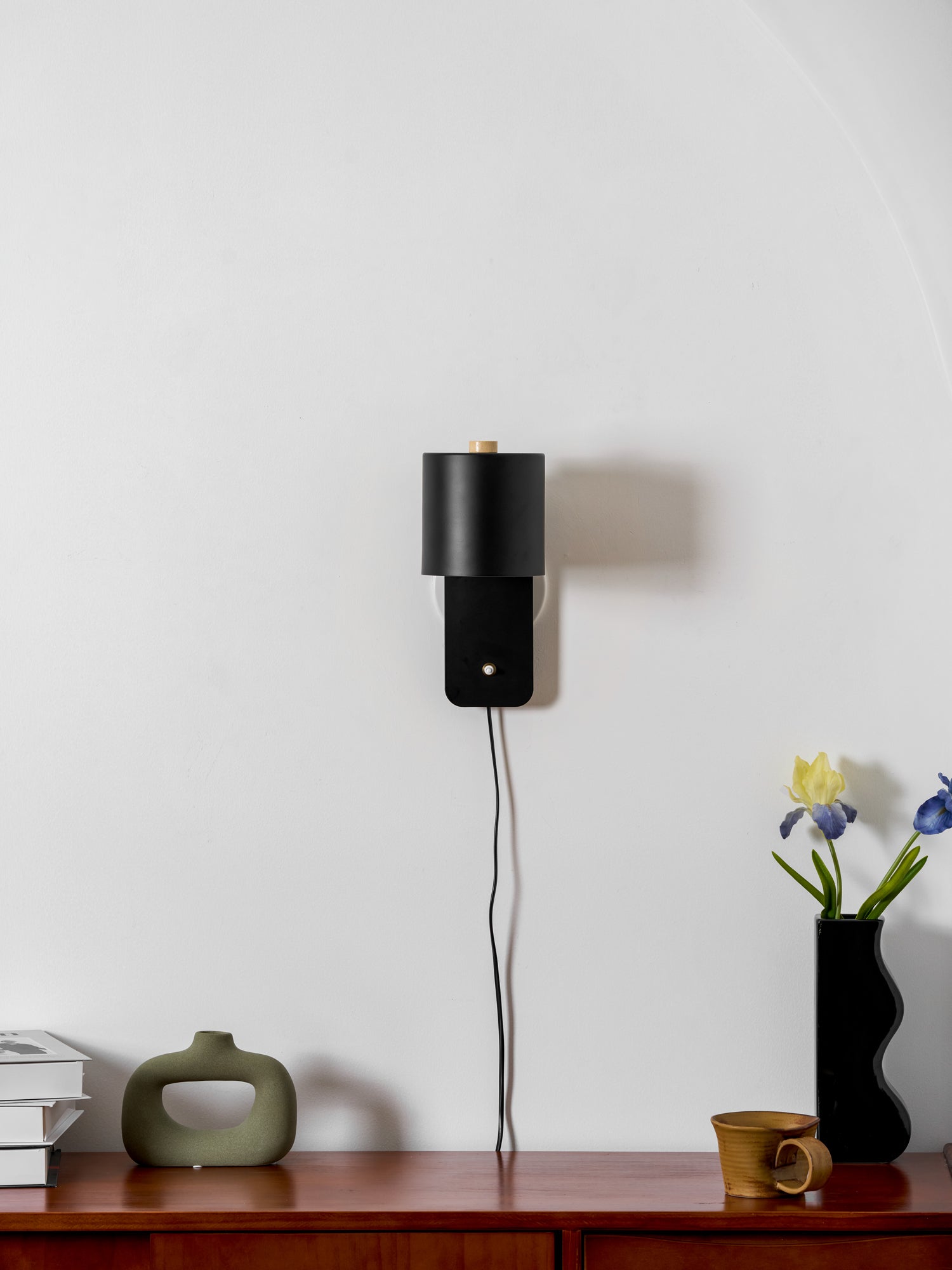 Minimalist cylinder wall lamp shown tilted upward on a wall