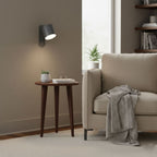 Rotating cylinder wall lamp beside a styled shelf