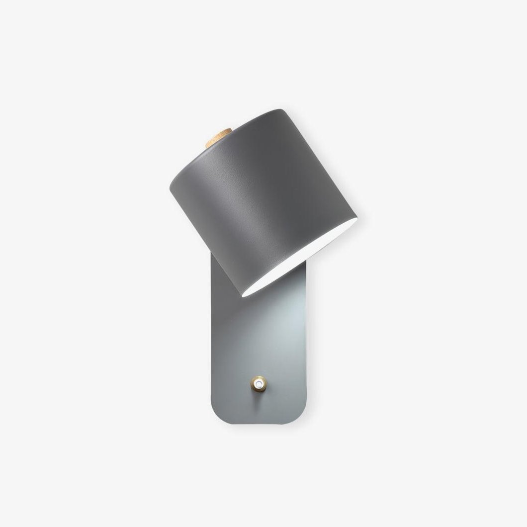 Cylinder wall lamp shown projecting from a painted wall