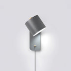 Rotatable cylinder wall lamp glowing softly beside a bed