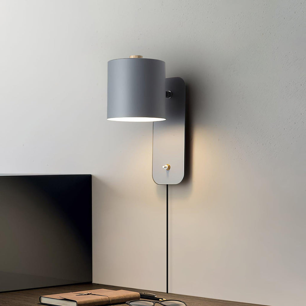 Cylinder wall lamp angled upward casting a soft glow on the wall
