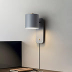 Cylinder wall lamp angled upward casting a soft glow on the wall