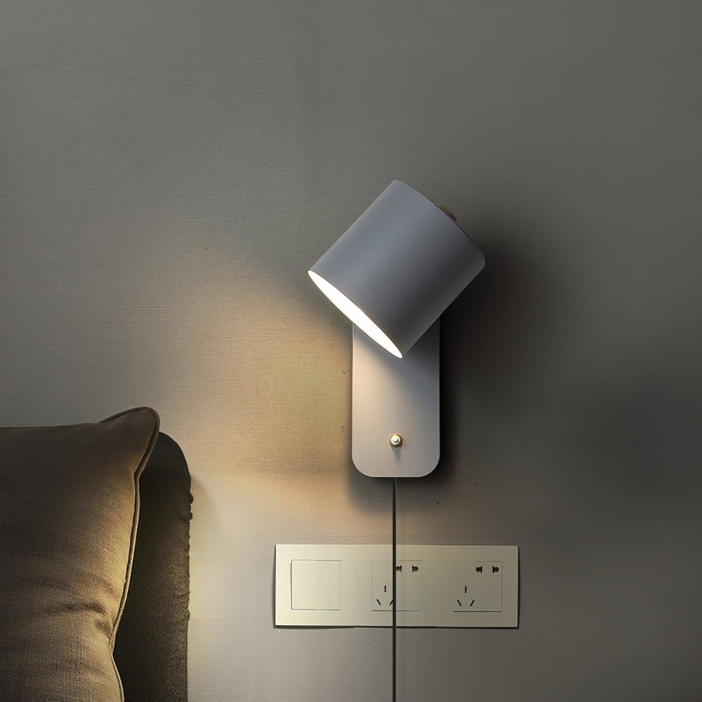 Metal cylinder wall lamp tilted to one side beside seating