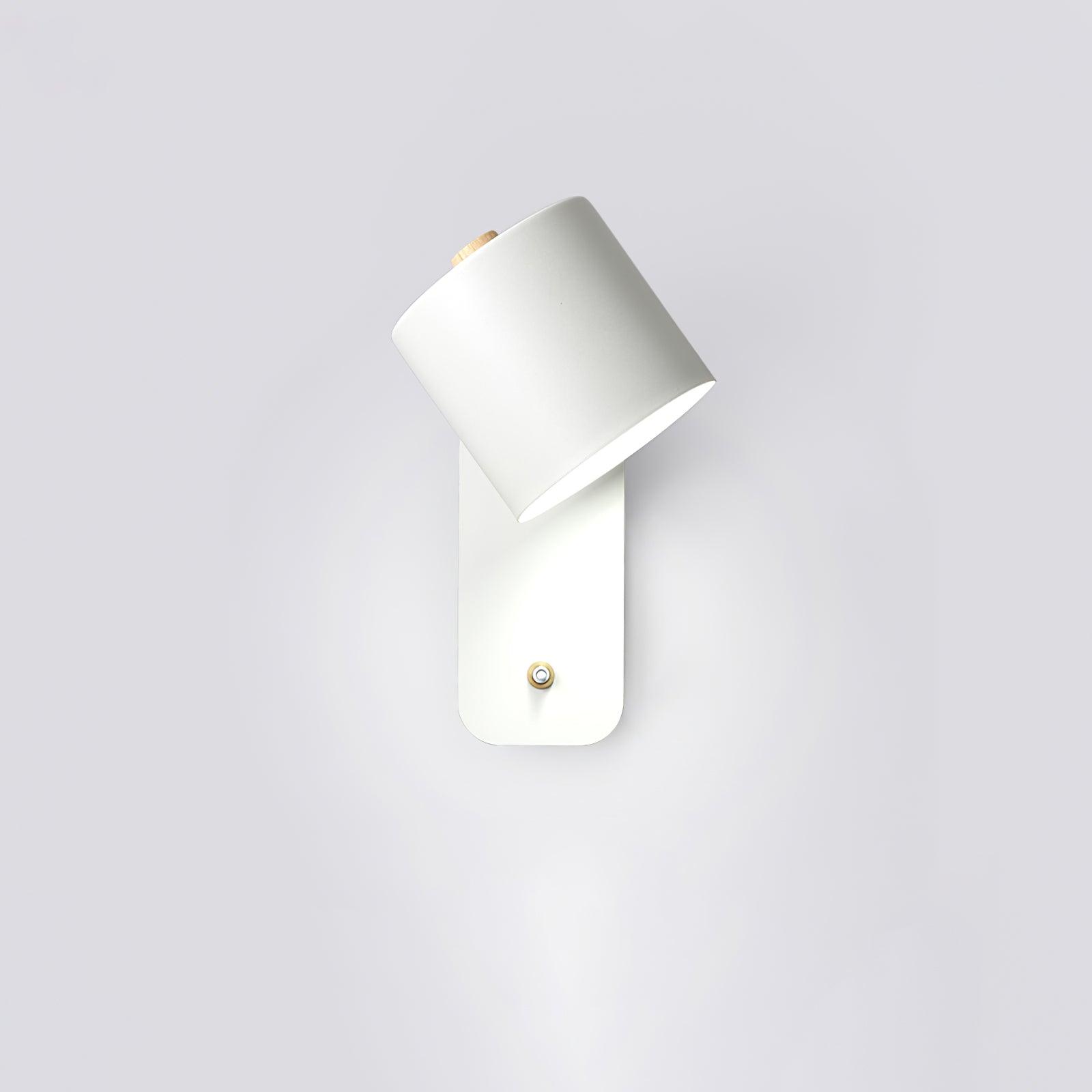 Cylinder wall lamp with rotating shade mounted beside a bed