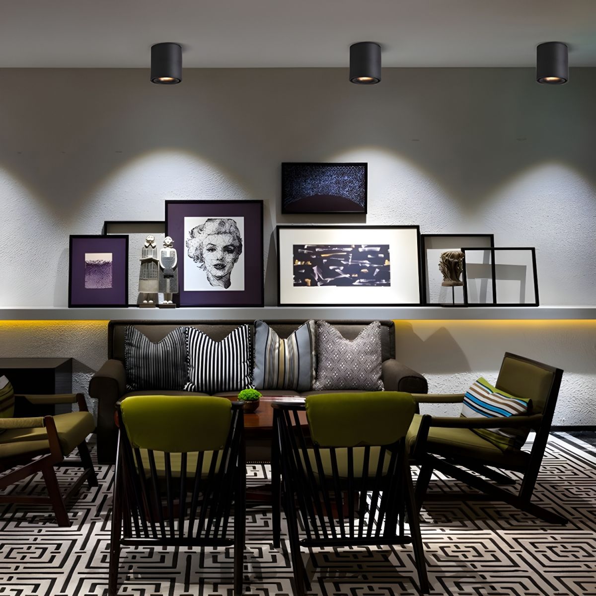 The same gallery wall of framed art is lit by three black Clérachic spotlights from a slightly different angle.