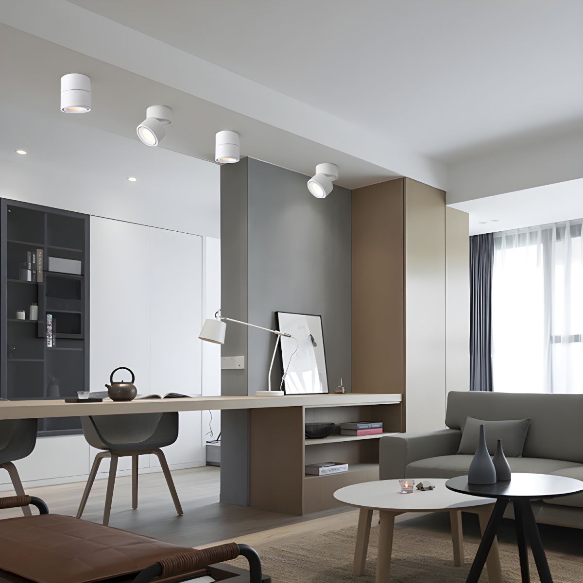 Unlit white Clérachic spotlights sit on the ceiling above a living room with a desk lamp and sofa.