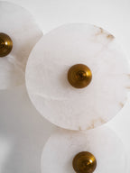 Close crop of three unlit alabaster discs, showing rust-toned veining and the ribbed brass centre.