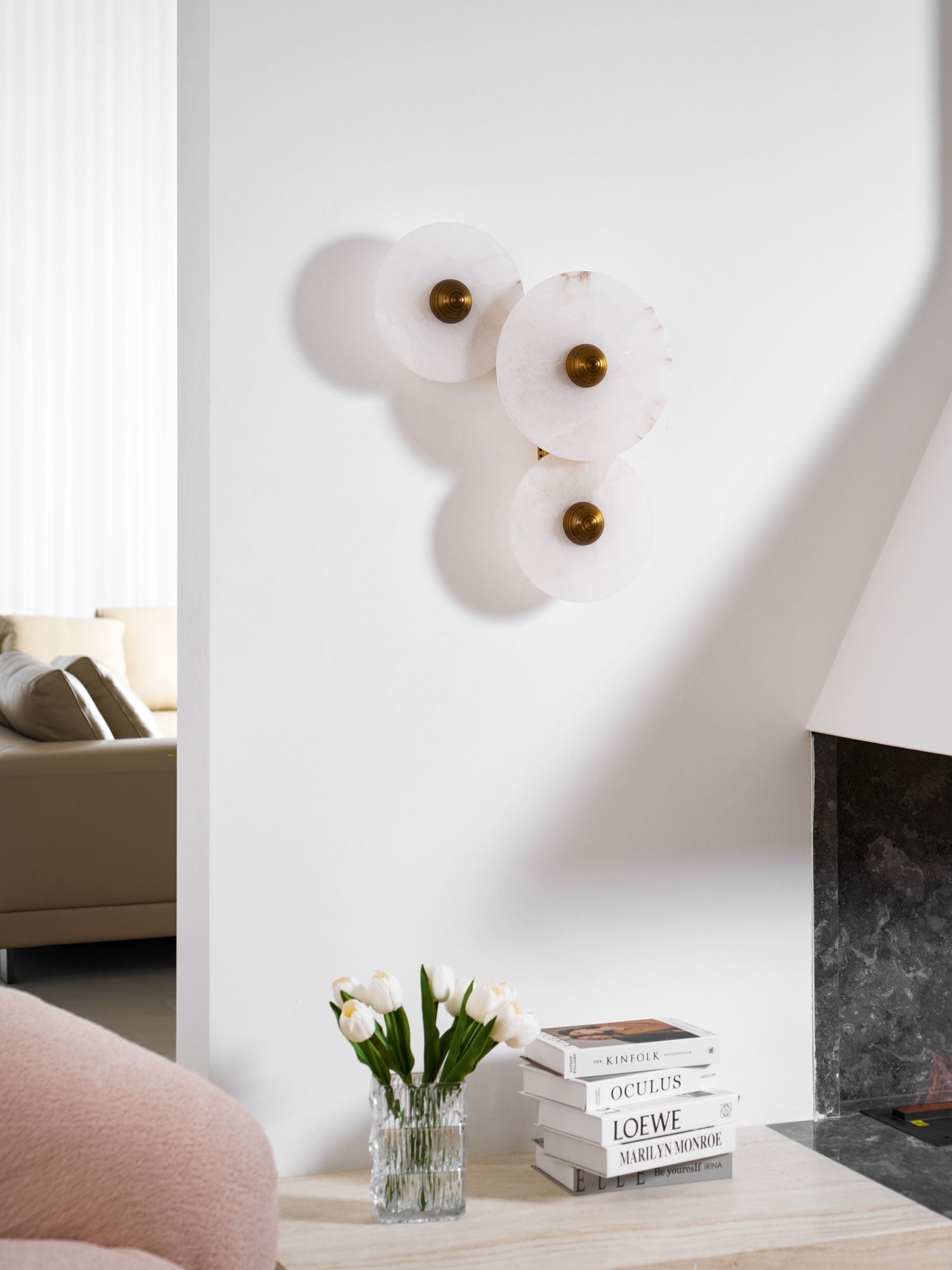 Three-disc alabaster cluster unlit on a white wall, a sofa and fireplace in the background.