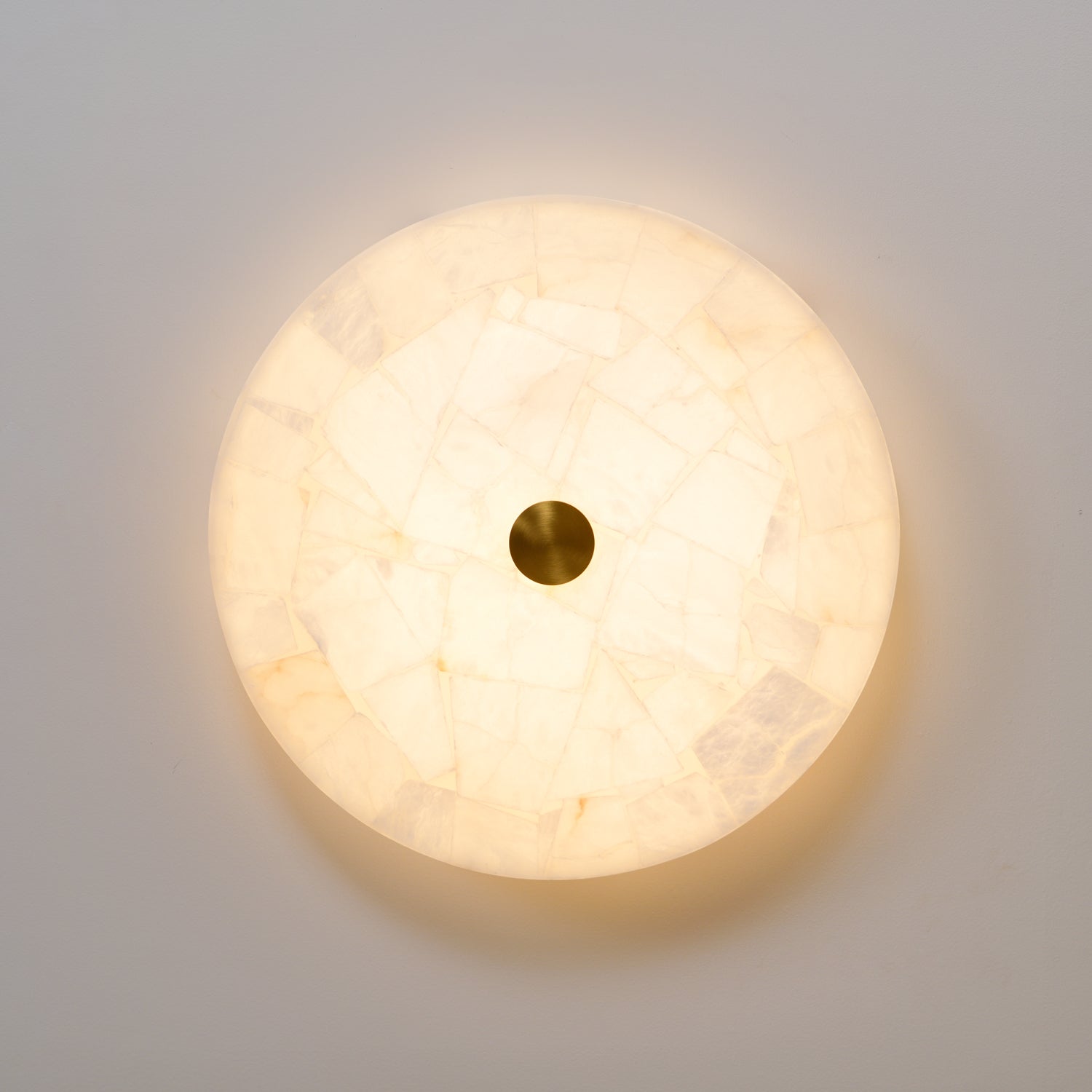 Straight-on view of the pale alabaster face, mosaic tiles glowing evenly around the brass cap