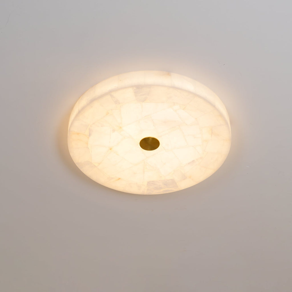 Kristy ceiling lamp lit head-on in cool white light, a faint halo spreading around the disc