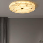 The lit flushmount seen from the far side of a bedroom, grey curtains framing the wall below