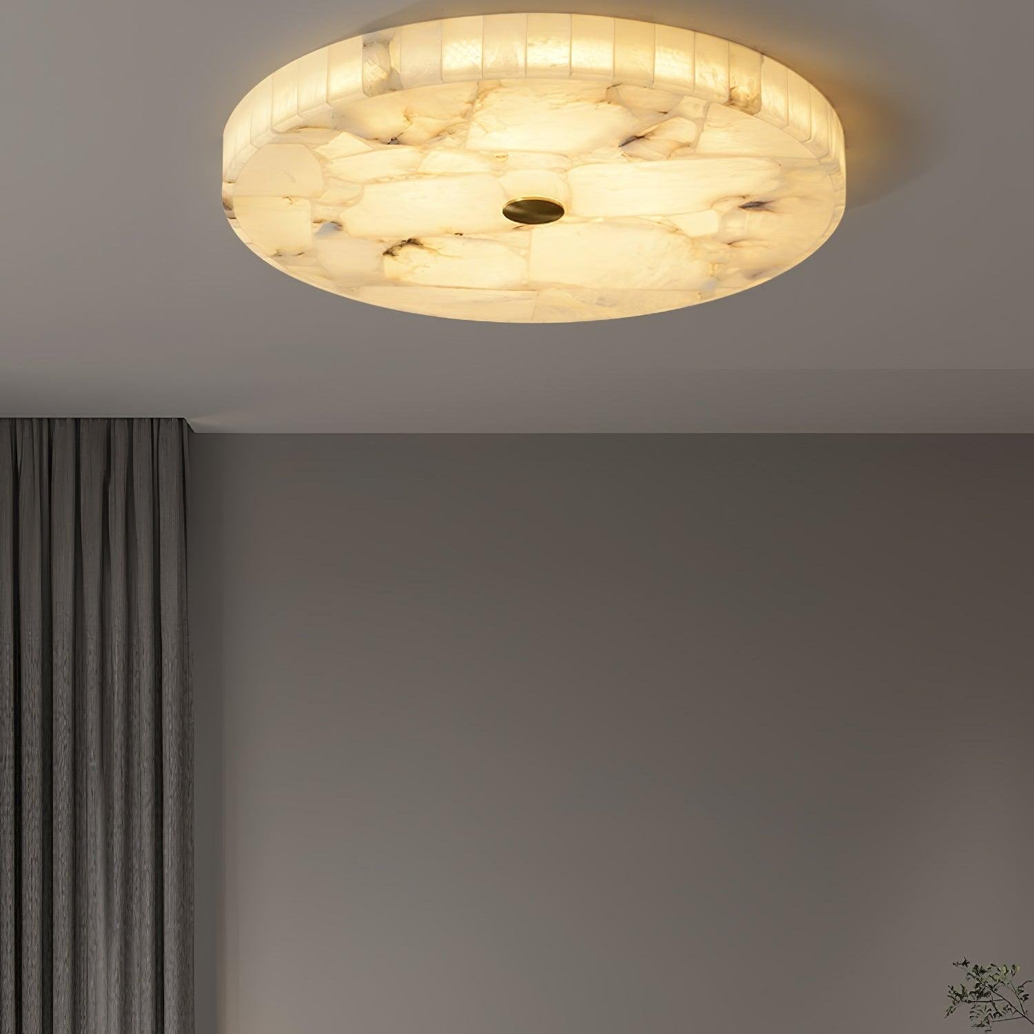 The lit flushmount seen from the far side of a bedroom, grey curtains framing the wall below