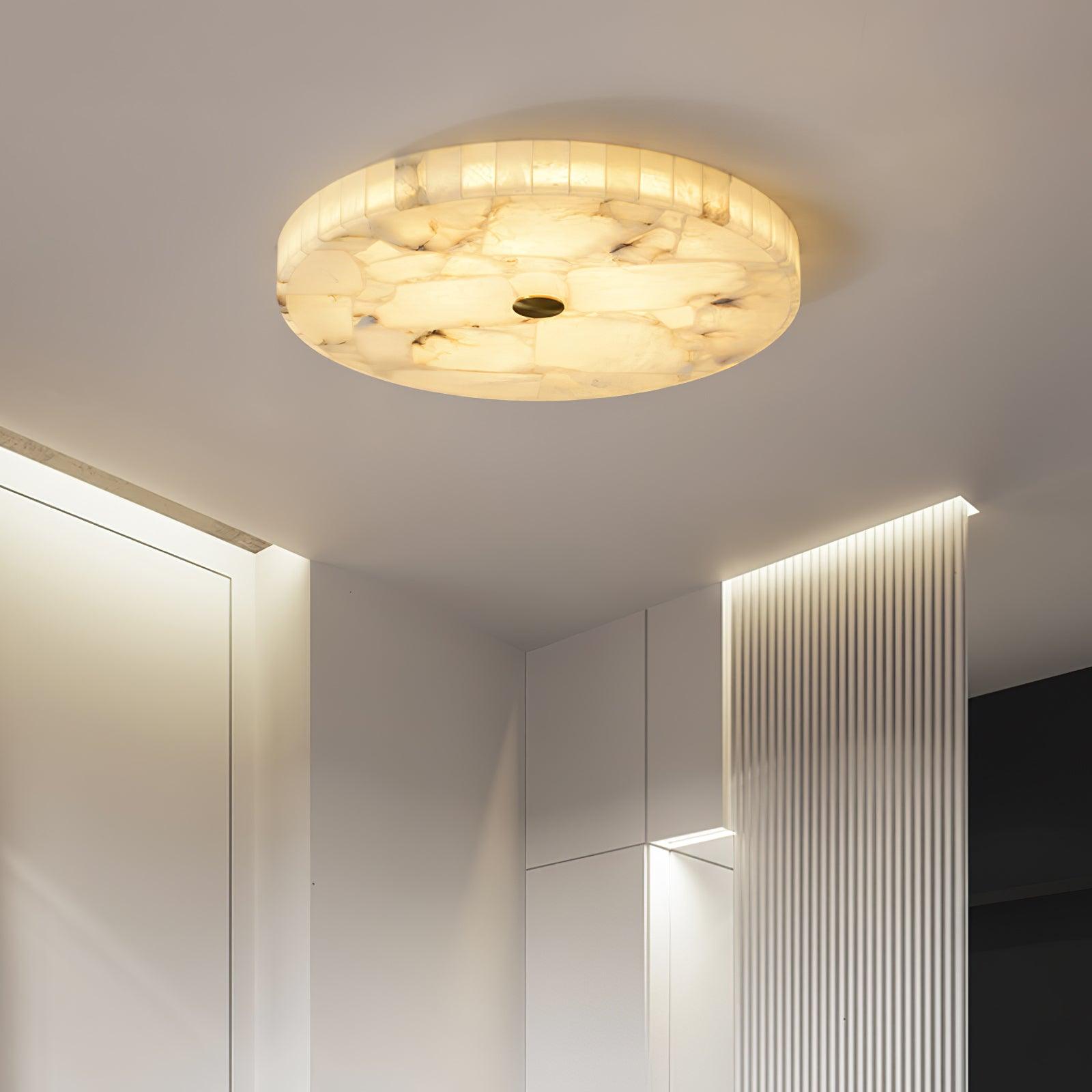 The flushmount above a white hallway, its warm light meeting the cove-lit fluted wall beyond