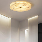 The alabaster flushmount lighting a white entrance hallway beside a fluted, backlit wall panel