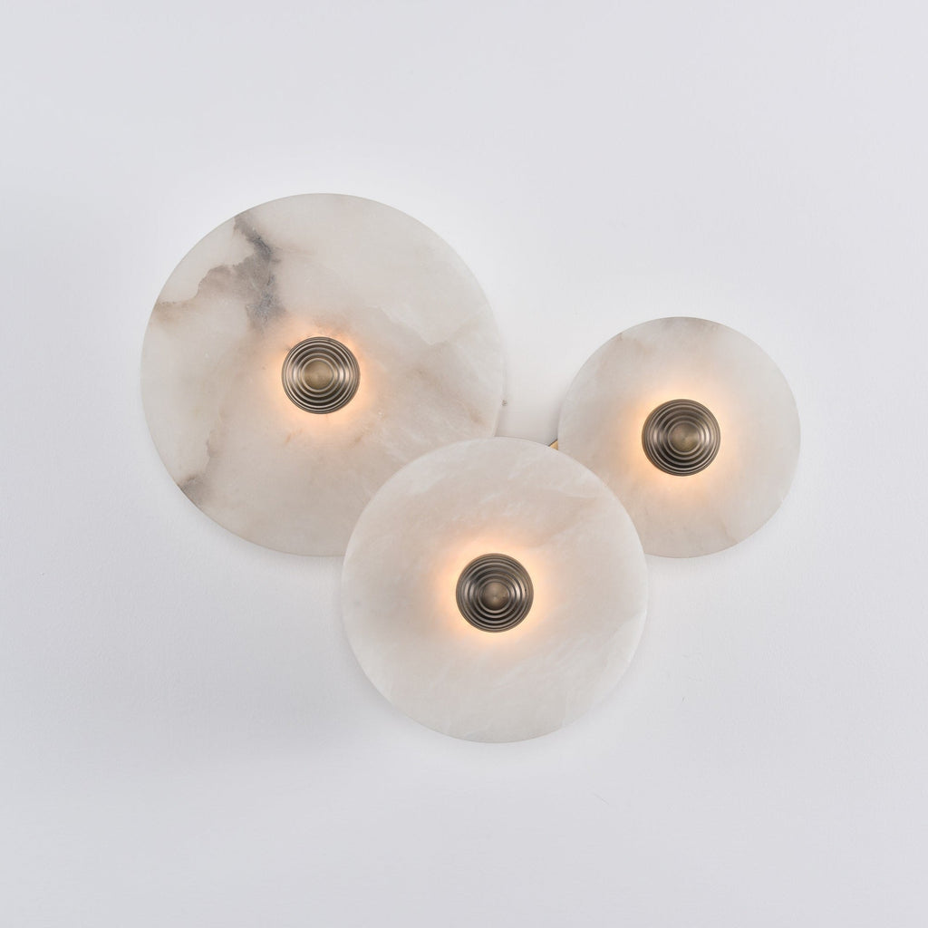 Three lit alabaster discs on white, the glow spreading evenly across each stone face.
