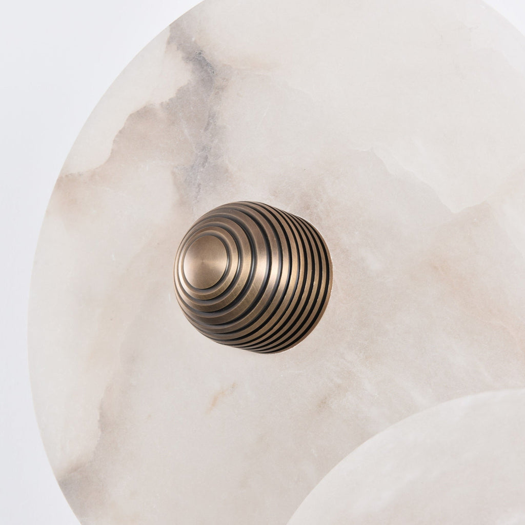 Close-up of the ribbed brass centre boss set into the alabaster disc, showing its concentric rings.