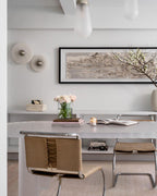 Two Clérachic overlapping sconces with brushed steel centres, unlit, on a white wall beside framed art in a dining nook.