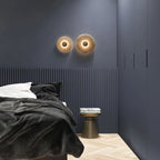 A Clérachic pair of lit sconces above a bed on a navy fluted wall, casting a warm gold halo.